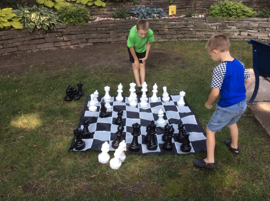 Boys playing chess with a giant chess set